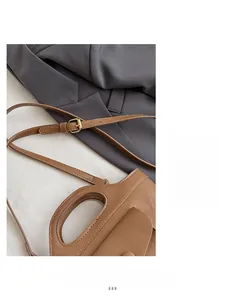 Detail of a brown leather basket bag featuring a golden buckle and round top handle