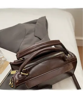Dettaglio borsa vintage in pelle cerata marrone con cerniera dorata e finiture metalliche