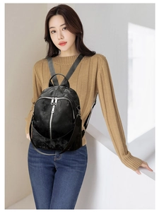 Detailansicht eines schwarzen Rucksacks mit silbernen Reißverschlüssen am Model