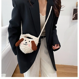 Détail macro du sac en tricot crème avec un motif mignon d'oreilles de chiot marron