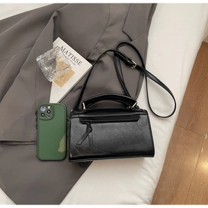 Dettaglio di una borsa a tracolla in pelle nera con finiture dorate e nappa decorativa