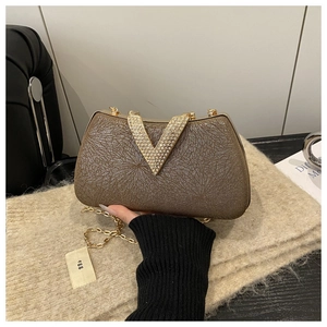 Detail of bronze evening bag with rhinestone V-logo and gold metal chain strap