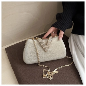 Detailed view of the champagne evening bag with sparkling diamond V-shaped metal buckle