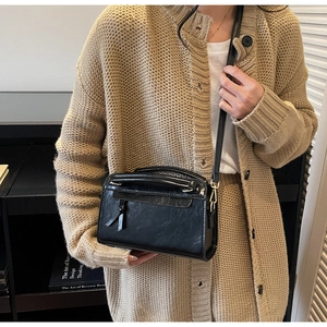 Dettaglio borsa quadrata nera indossata con maglione in maglia beige per stile quotidiano