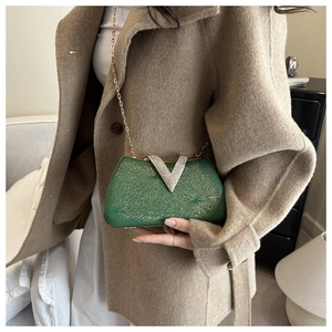 Detail of emerald green box clutch with gold web texture and rhinestone V-clasp