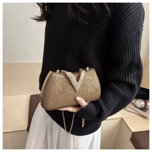 Detail of gold clutch bag with chain strap and V-shaped crystal buckle on hand