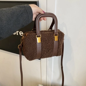 Detailed close-up of brown plush faux shearling bag with leather strap and gold buckle
