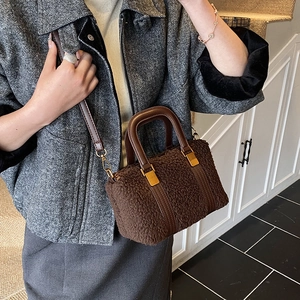 Close-up of brown plush faux fur handbag with leather handles and gold metal buckles