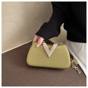 Detail of a golden evening clutch with V-shaped rhinestones and chain strap