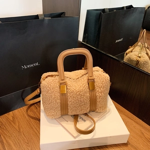 Detail of plush beige faux shearling handbag with camel leather handles on a display