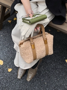 Detailed shot of plush apricot boston bag with brown leather straps on outdoor bench