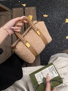 Detail of beige plush handbag with brown leather handles and gold metal buckles