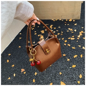 Vue détaillée du sac seau vintage marron avec breloques cerises et fermoir doré rotatif