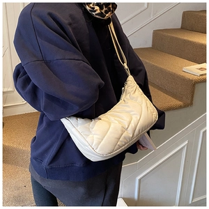Detail of cream quilted crossbody bag featuring wave patterns and soft nylon texture