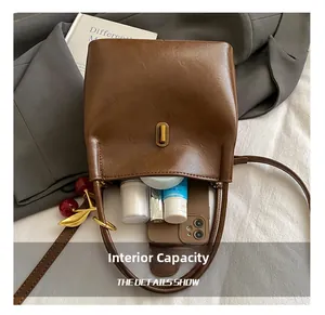 Sac seau en cuir marron avec boucle dorée montrant l'espace pour téléphone et cosmétiques