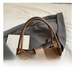 Détail d'un sac seau vintage en cuir marron avec fermoir en J et pendentif cerise