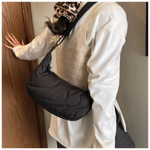 Detail of black quilted shoulder bag featuring soft wave stitching and secure zipper