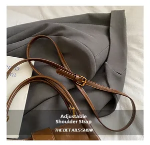 Détail de la bandoulière réglable avec boucle dorée sur un sac rétro marron