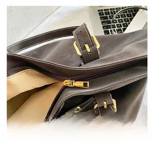 Close-up of golden zipper hardware and fine white stitching on a brown leather tote bag