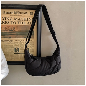 Detail of black quilted hobo bag with adjustable strap and retro wave stitching