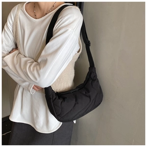 Detail of black quilted half-moon shoulder bag with wave stitching and adjustable strap