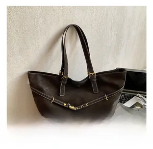 Detail of dark brown tote bag featuring white contrast stitching and gold metal hardware