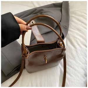 Détail d'un sac seau marron vintage avec texture en cuir mat et fermoir doré rotatif