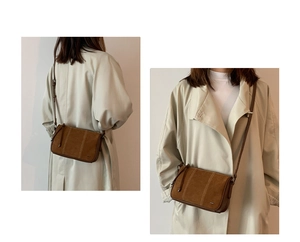 Detail view of brown suede crossbody bag with contrast stitching and adjustable strap