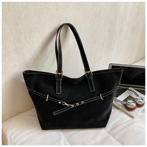 Close-up of black tote bag featuring white contrast stitching and gold metal buckles