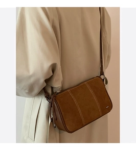 Detailed side view of a brown vintage suede shoulder bag with vertical stitching