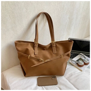 Brown suede tote bag with metal buckle detail shown in a functional office setting