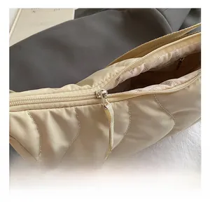 Detailed macro view of metal zipper and quilted nylon texture on beige shoulder bag