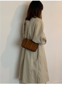 Brown retro suede shoulder bag styled with a beige trench coat for a casual look