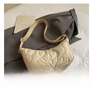 Close-up of cream wave quilted hobo bag with a wide strap on a minimalist coat background