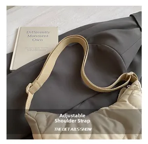 Detail of adjustable wide shoulder strap on beige quilted crescent crossbody bag