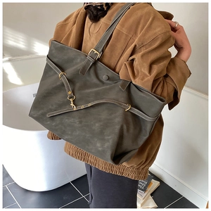 Detail of olive green tote bag with matte texture and adjustable strap on a model