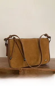 Close-up of caramel brown suede shoulder bag with smooth leather edges and metal hardware
