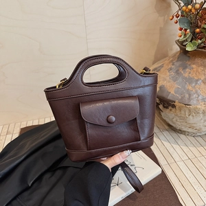 Brown leather trapezoid tote bag with oval cutout handle and gold hardware detail