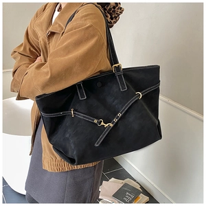 Detail of black leather tote bag featuring white contrast stitching and gold metal hook