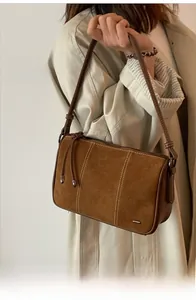 Detail of retro brown suede shoulder bag featuring contrast white double stitching accents