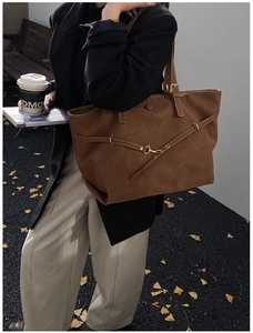 Detailed side view of a large caramel brown tote bag with decorative gold buckle strap
