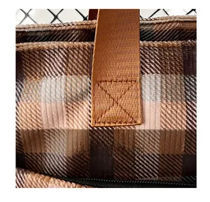 Close-up of brown plaid tote bag showing reinforced X-shaped stitching and textured fabric