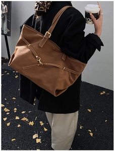 Street style shot of a vintage brown large leather tote bag with gold metal buckle