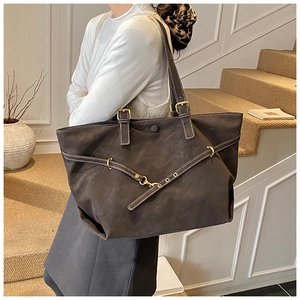 Detail of dark brown matte leather tote bag with gold buckle and white contrast stitching