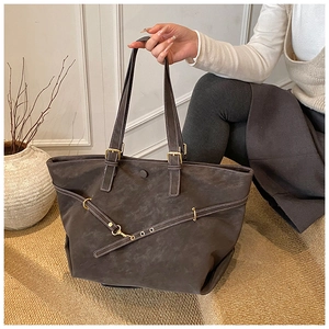 Detail of dark brown tote bag showing matte texture and gold adjustable buckle