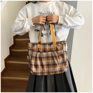 Detail of checkered canvas tote bag with yellow straps and pleated front pocket