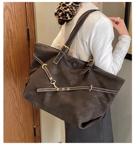 Detail of dark brown faux suede tote bag with golden metal hardware and strap