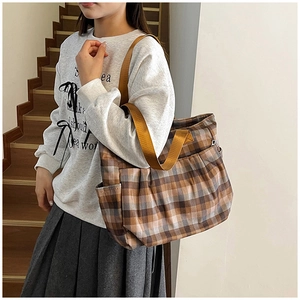 Detail of retro plaid canvas tote bag with side pocket and brown shoulder strap