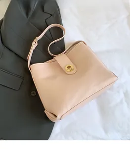 Detail of light pink leather bucket bag featuring a round golden metallic twist lock
