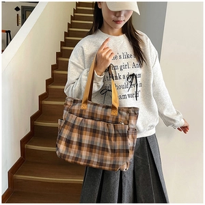 Detail shot of large canvas tote bag featuring classic plaid pattern and yellow handles
